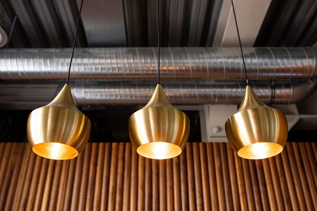 businessfotos und unternehmensfotos in einer location schwarze Küche und braune bar aus holz mit Bali Elementen Golde Lampen in München Inneneinrichtung nobel mit offener Küche fotografiert von der Berliner Fotografin aus berlin