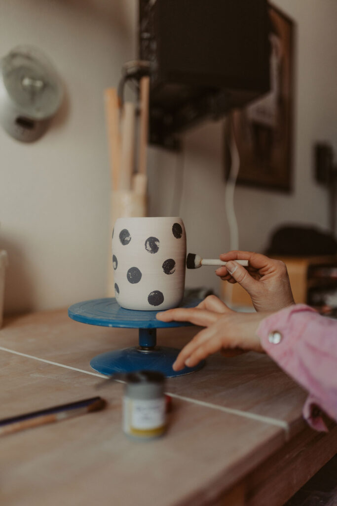 eine Töpferin in berlin lässt sich fotografieren und sie töpfert an der Drehscheibe Tassen und Vasen. ihr Atelier ist im Funkhaus in berlin und sie hat mich beauftragt ihre Business fotos zu machen.