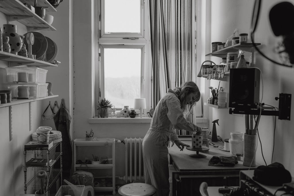 eine Töpferin in berlin lässt sich fotografieren und sie töpfert an der Drehscheibe Tassen und Vasen. ihr Atelier ist im Funkhaus in berlin und sie hat mich beauftragt ihre Business fotos zu machen.